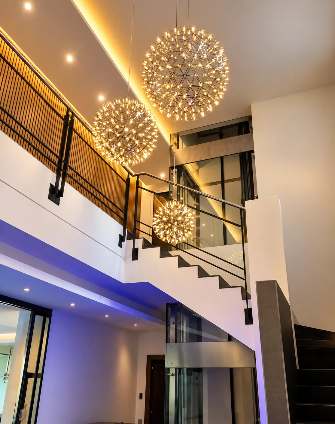Espacio interior a doble altura con lámparas de diseño y escalera en Villa Alba, Marbella