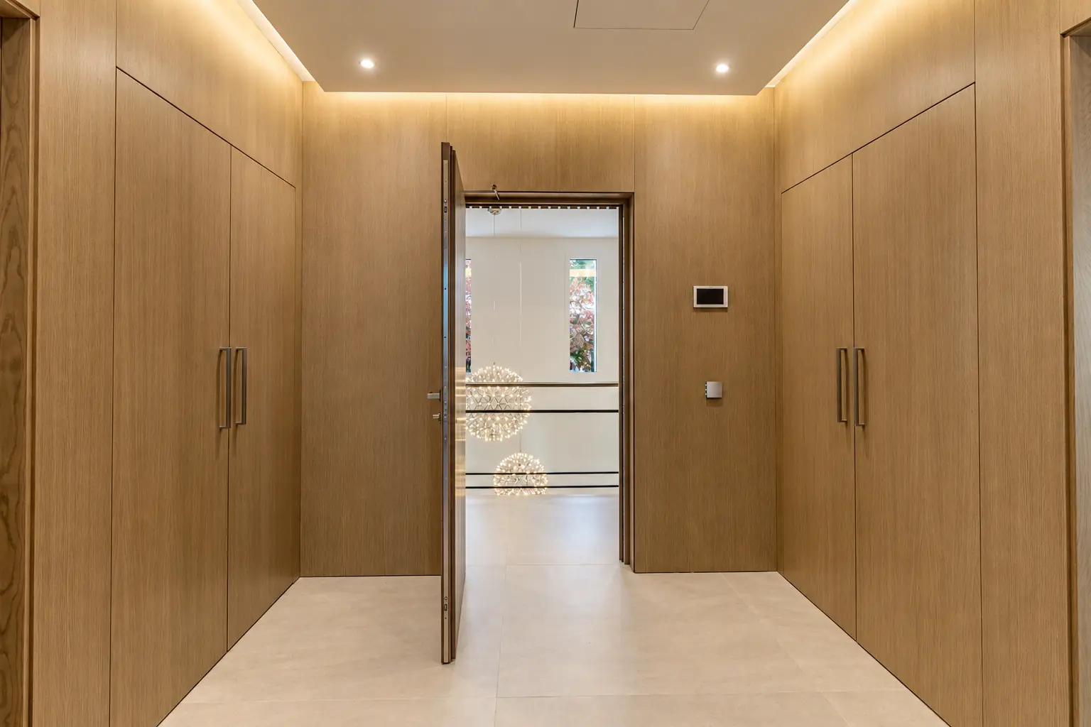 Recibidor con armarios de madera a medida e iluminación indirecta en Villa Alba, Marbella